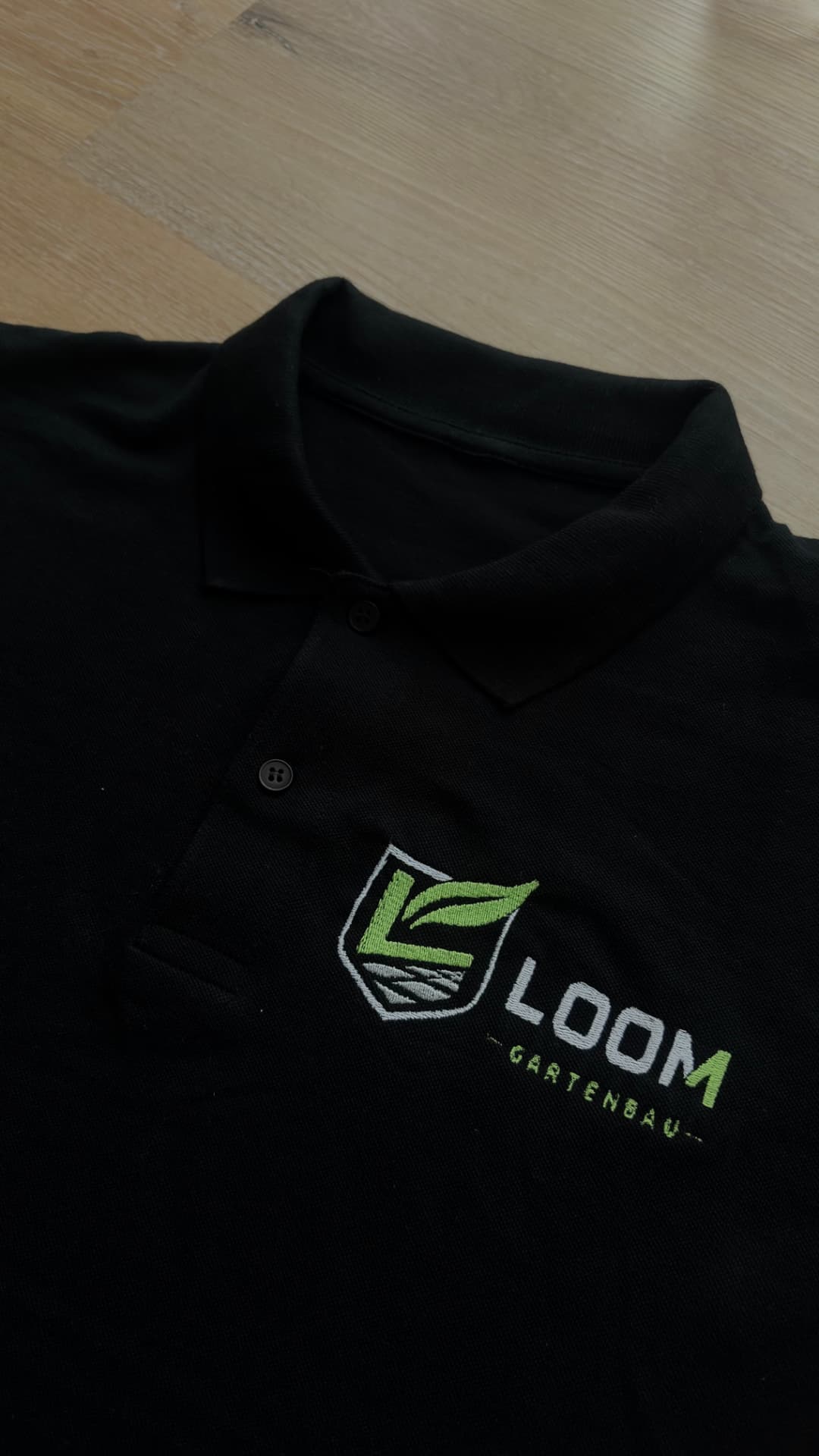 Schwarzes Poloshirt mit gesticktem LOOM Gartenbau Logo