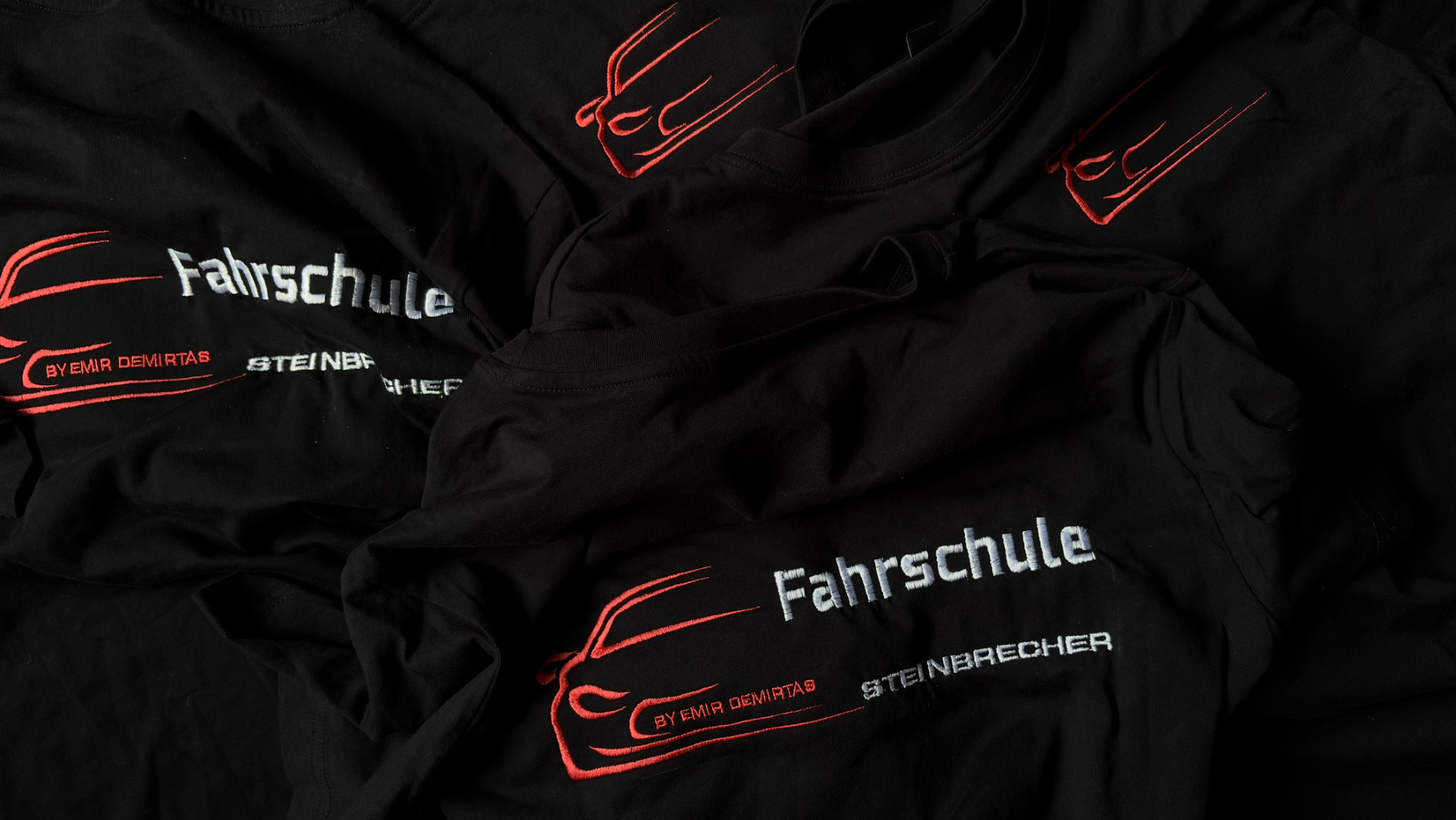 Schwarze Shirts mit gestickter Fahrschule Steinbrecher Stickerei in Rot und Weiß